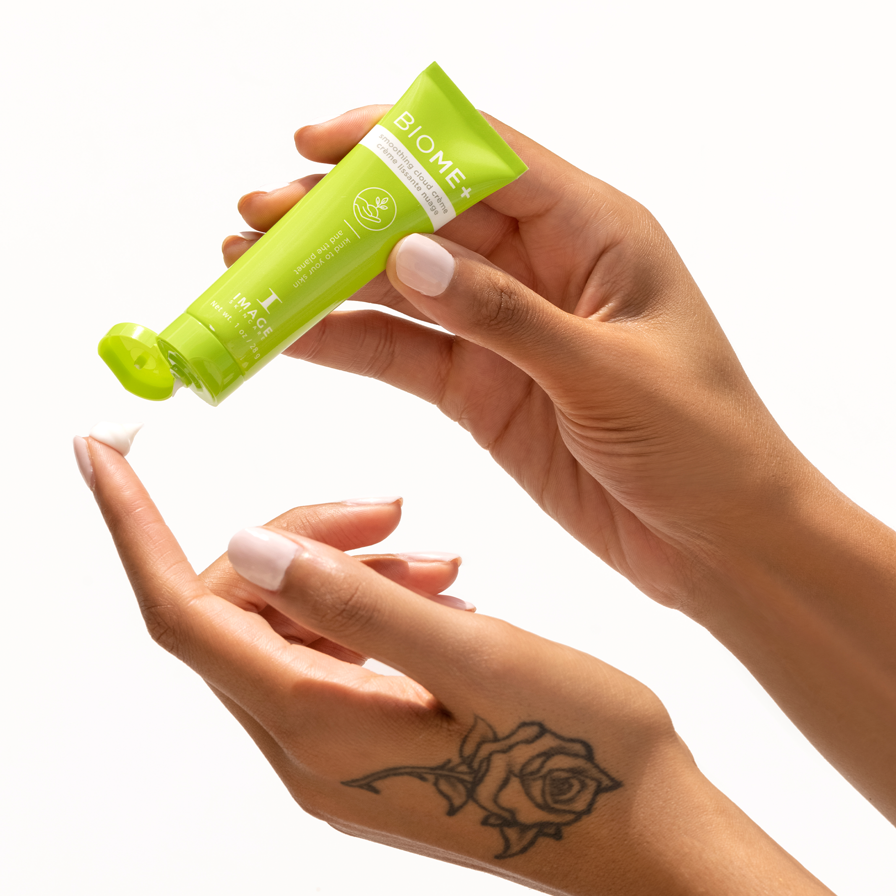 model holding travel size tube of biome+ smoothing cloud creme and dispensing creme onto finger