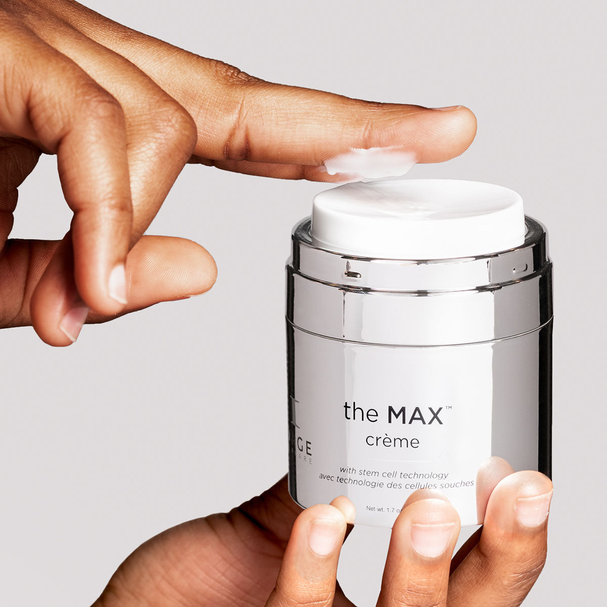 model holding open jar of the MAX creme and dispensing product onto finger