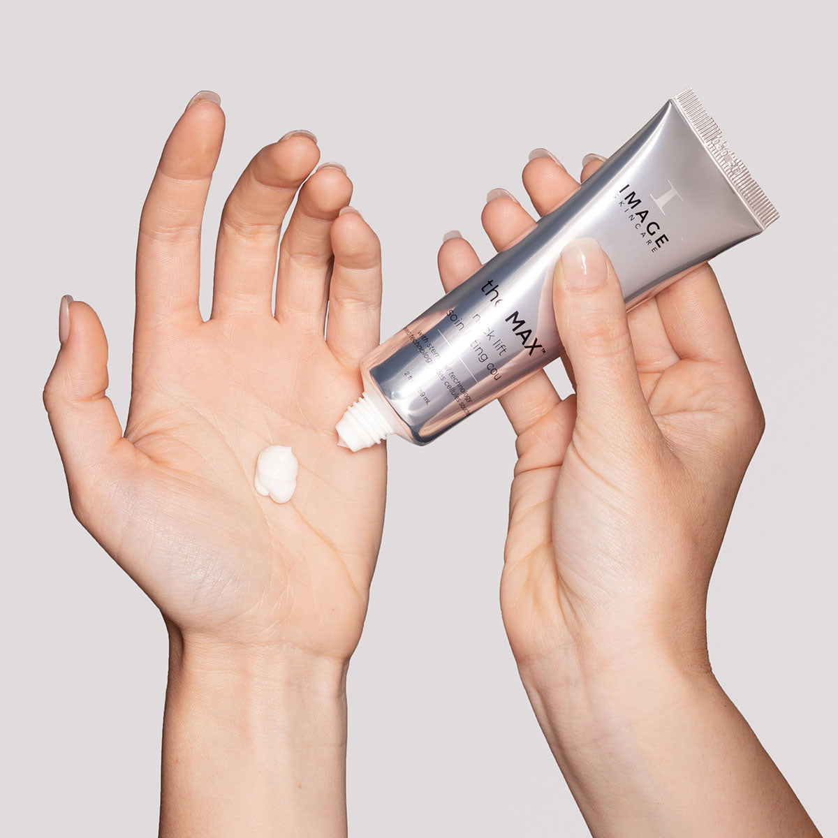 model hands holding neck lift tube in one hand and dispensing product into palm